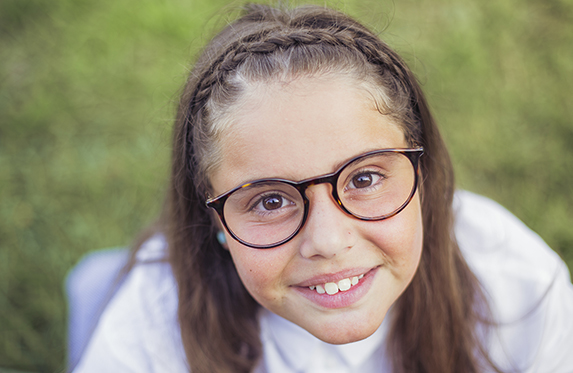 young girl with glasses looking up